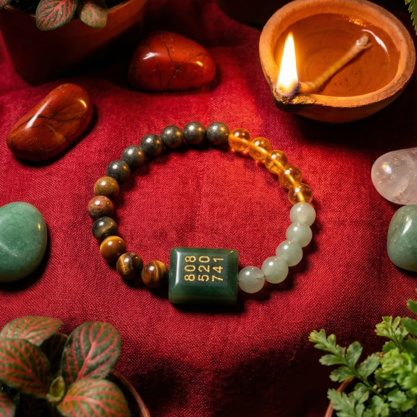 Beaded bracelet with a green charm on a red fabric background with stones and a candle.