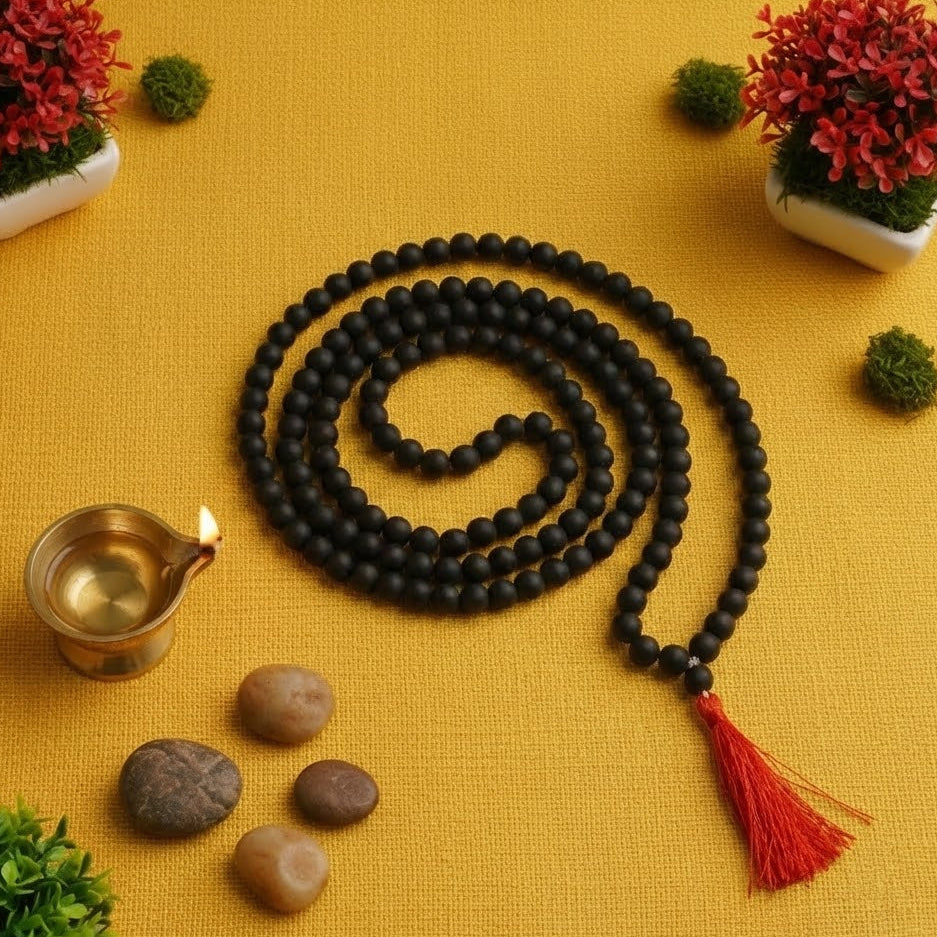 Black beaded rosary with a red tassel on a yellow background with decorative elements.