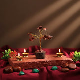 Decorative setup with a small tree, candles, and stones on a red fabric background