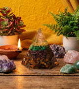 Crystal pyramid with various crystals and plants on a wooden surface against a yellow wall.