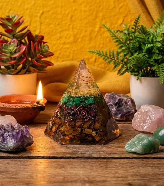 Crystal pyramid with various crystals and plants on a wooden surface against a yellow wall.