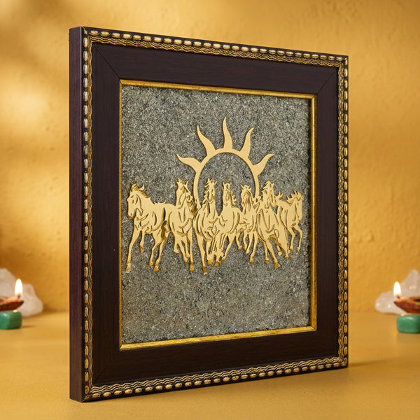 Decorative wall art with horses and sun design in a black frame on a yellow wall.