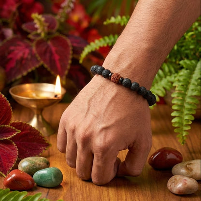 Hand wearing a beaded bracelet on a wooden surface with stones and plants