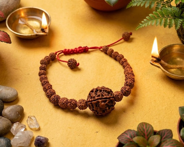Bracelet made of wood beads on a yellow surface with candles and plants
