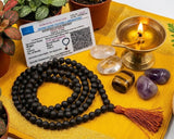 Meditation tools including a mala, crystals, and a candle on a yellow mat with plants around.