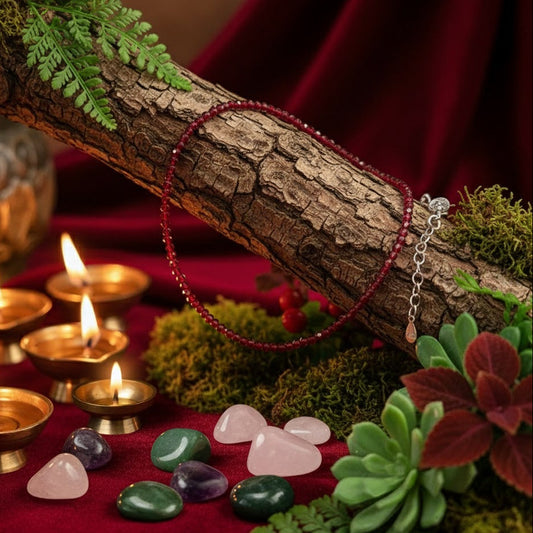 Bracelet on a branch with candles, crystals, and plants on a red fabric background