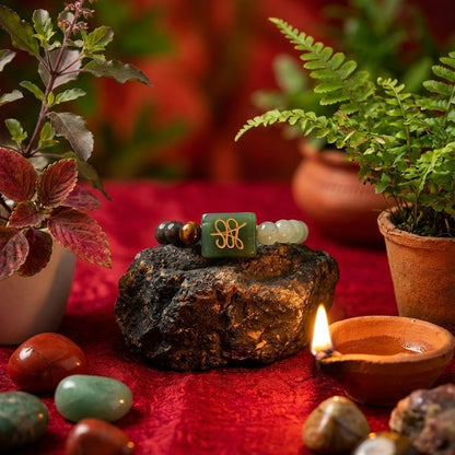 Decorative setting with stones, plants, and a lit candle on a red surface