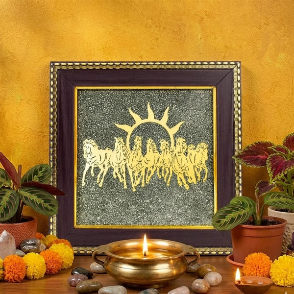 Decorative setup with framed artwork, candles, and plants on a wooden surface against a yellow wall.