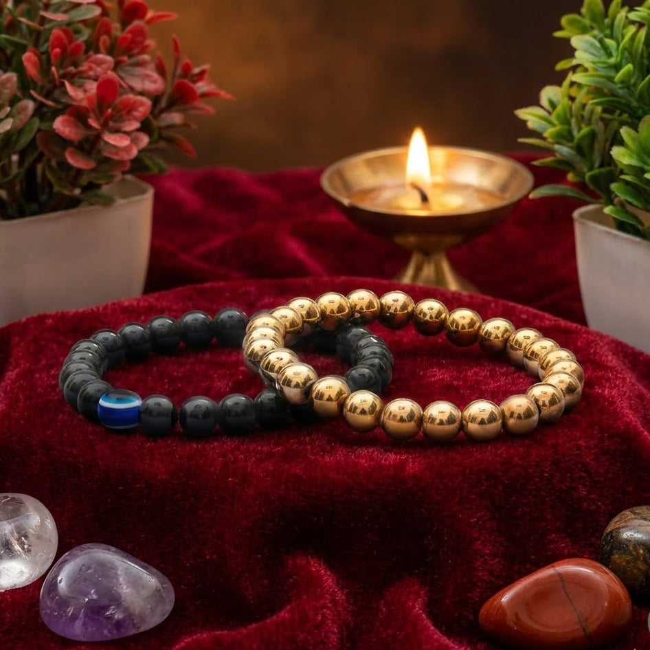 Two beaded bracelets on a red fabric with crystals and a candle in the background