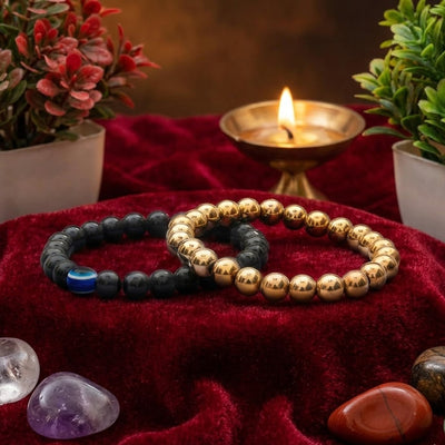 Two beaded bracelets on a red fabric with crystals and a candle in the background