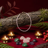 Necklace on a log with candles, stones, and berries on a red surface
