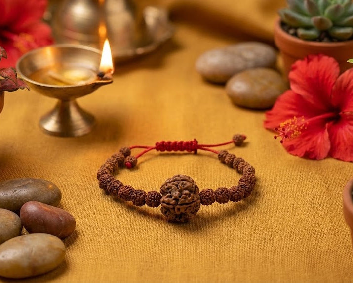 Bracelet with red cord on a yellow surface with flowers and stones