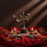 Decorative setup with a small tree, candles, and fruits on a red cloth.
