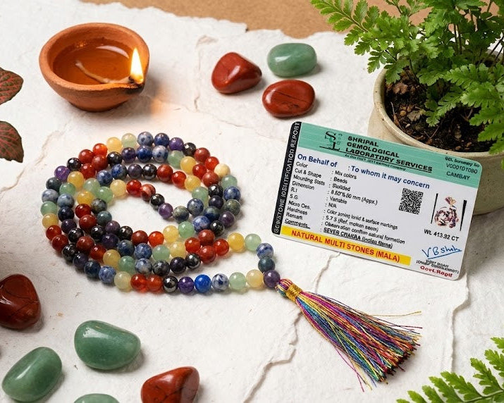 Colorful beaded bracelet with tassel, crystals, and a card on a white surface with plants.
