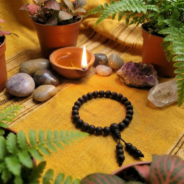 Black beaded bracelet on a yellow fabric with plants and stones