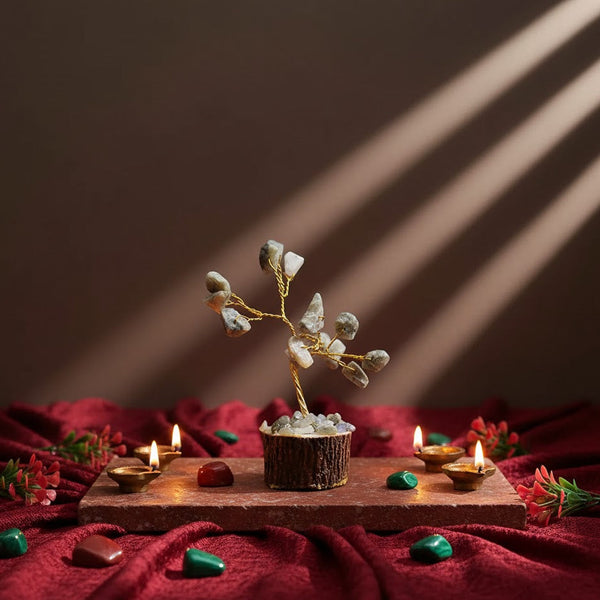 Small tree in a pot on a wooden board with candles and stones on a red fabric background