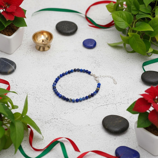 Blue beaded bracelet on a white surface with decorative ribbons and plants.